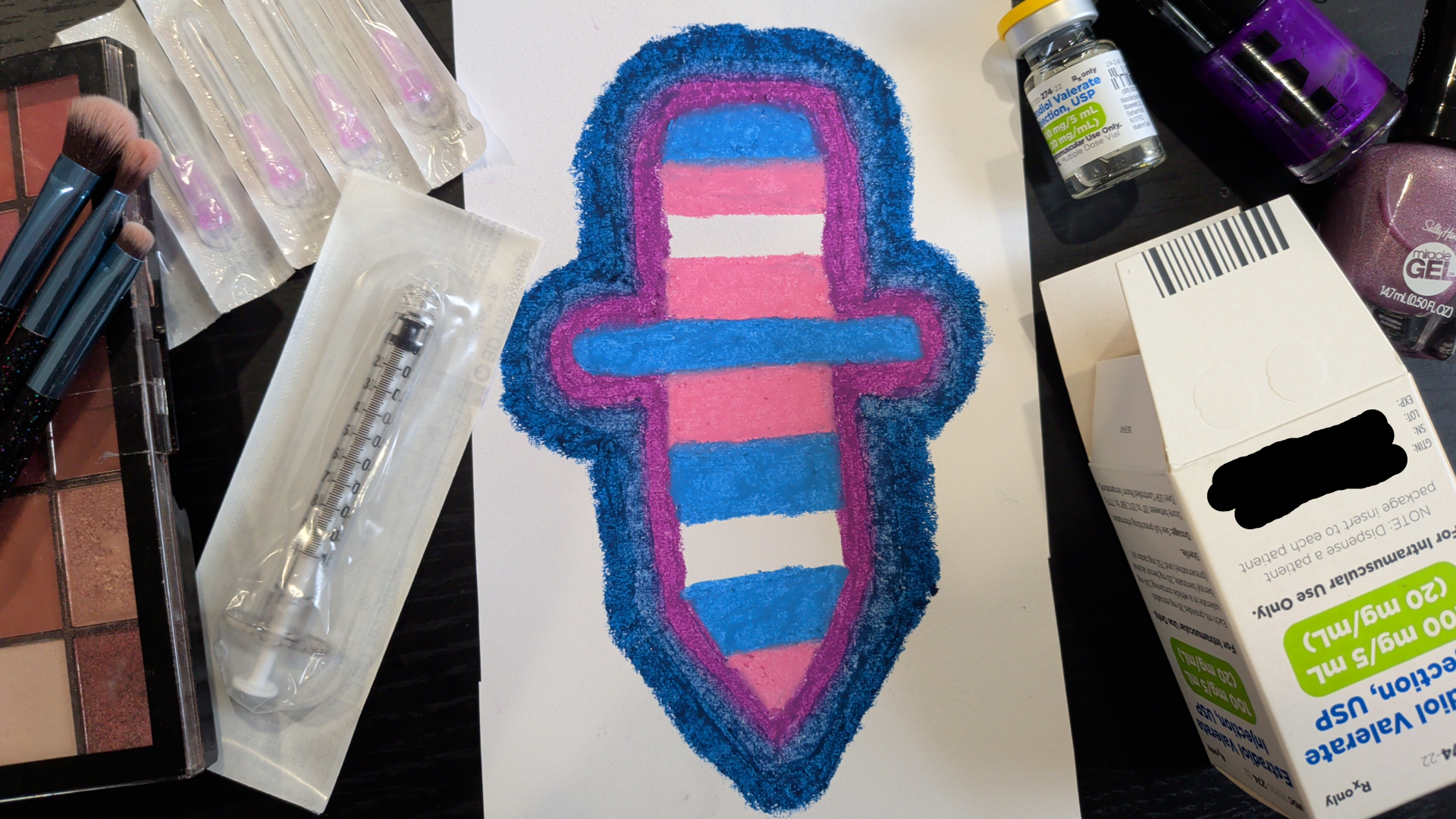 Picture of a drawing of a knife made of trans flag colors, surrounded by estradiol injection supplies, makeup, and nail polish.